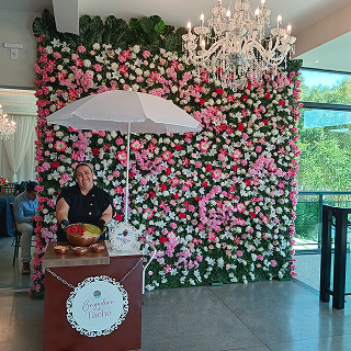 Estação de brigadeiro de tacho em salão com parede de flores